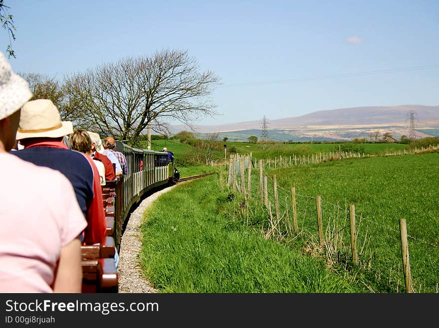 Narrow gauge passenger train filled with tourists travelling through the countryside