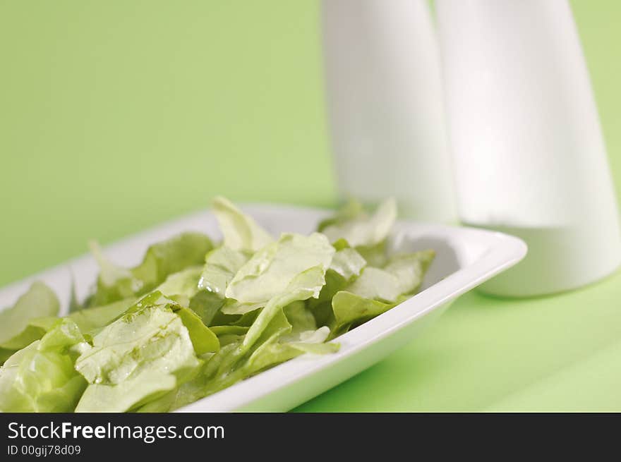 Oil to the fresh lettuce on the green background