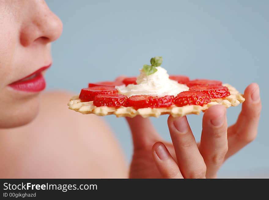 The woman eats strawberries on the blue background. The woman eats strawberries on the blue background