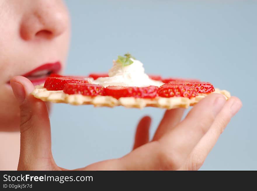 The woman eats strawberries on the blue background. The woman eats strawberries on the blue background