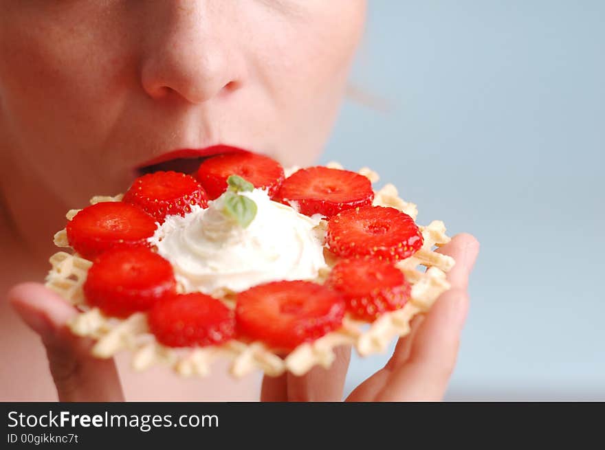 The woman eats strawberries on the blue background. The woman eats strawberries on the blue background