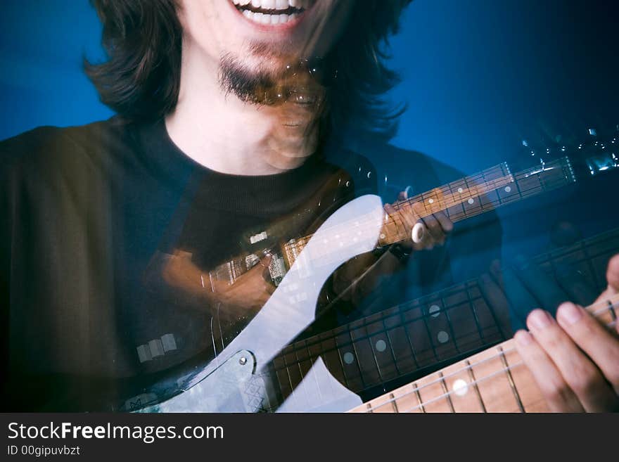 Rocker playing electric guitar over blue background, zoom and strobe lighting. Rocker playing electric guitar over blue background, zoom and strobe lighting.