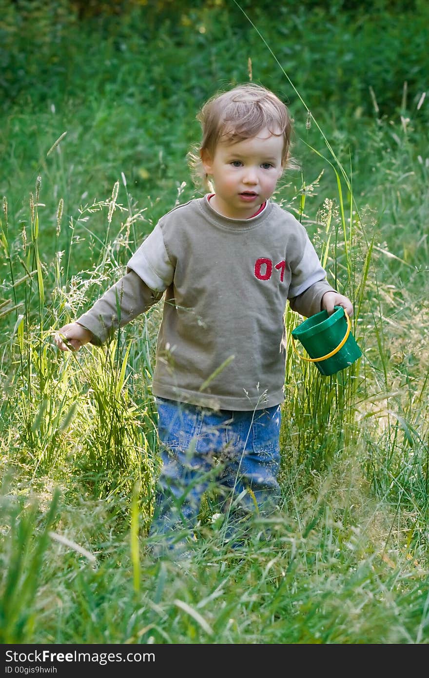 Lovely child plays to a dense grass during sunsete in beams of the sun. Lovely child plays to a dense grass during sunsete in beams of the sun