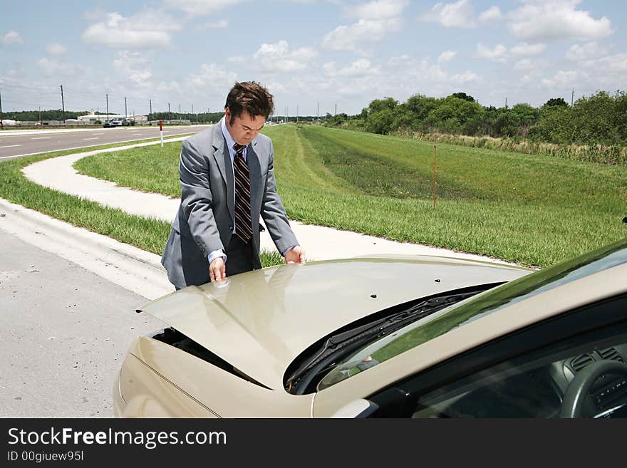 A businessman with car trouble checking under the hood. A businessman with car trouble checking under the hood.