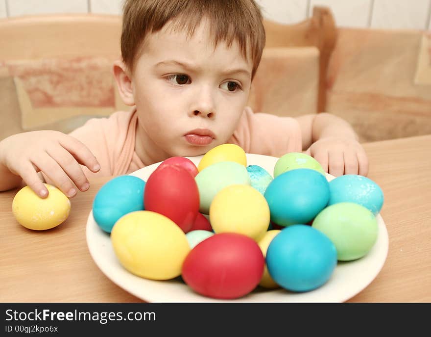 Emotions of the boy and easter eggs on a table