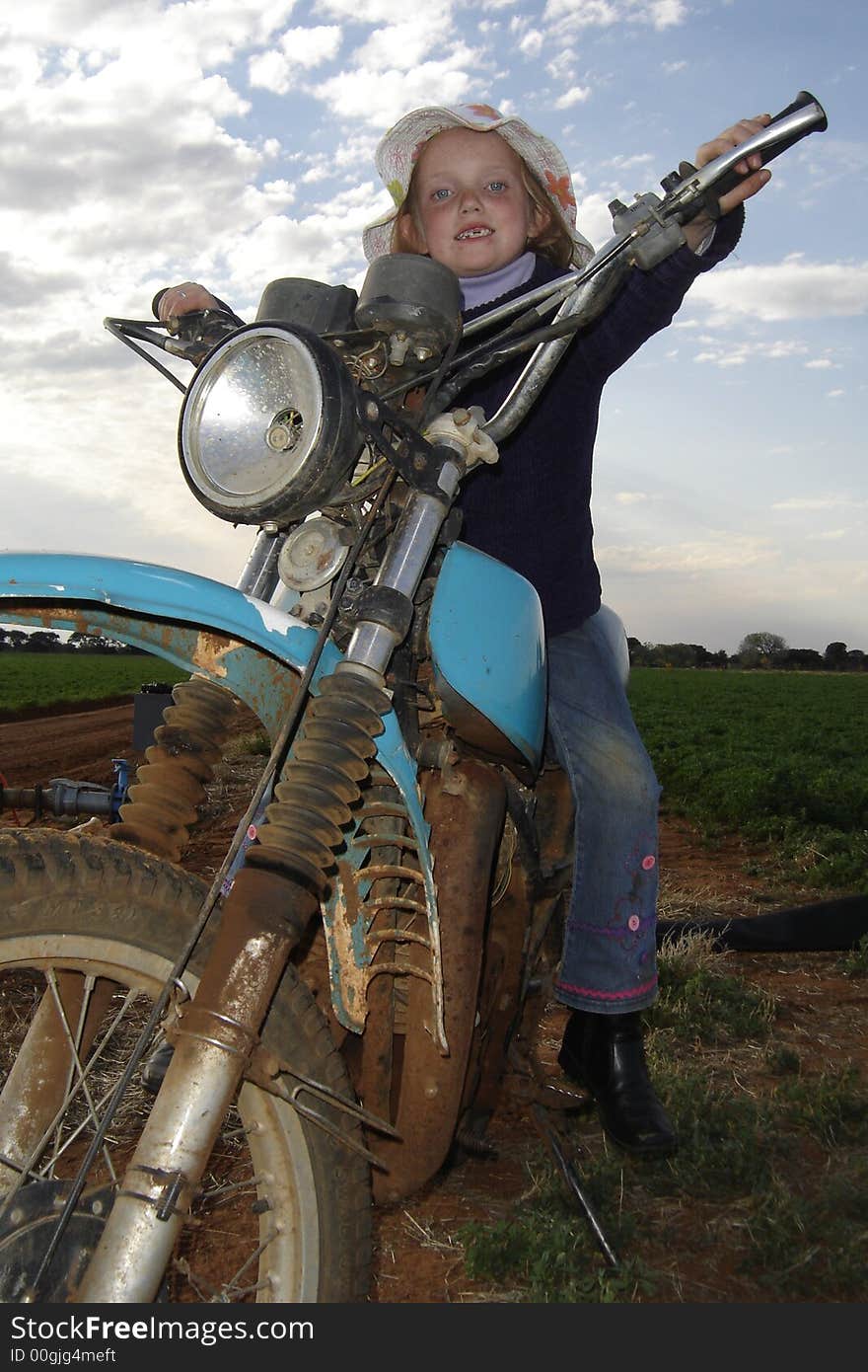 Young girl on old farm motorcycle. Young girl on old farm motorcycle.