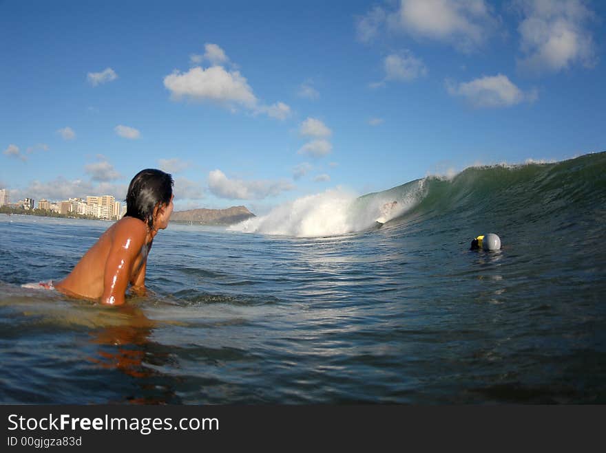 A surfer watching another surfer getting a tube ride getting filmed. A surfer watching another surfer getting a tube ride getting filmed