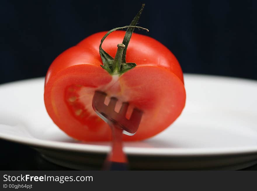 Tomato with stem on the plate and black background