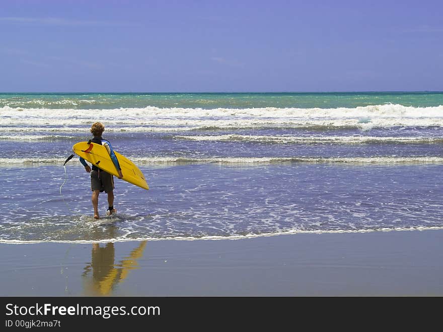 A surfer enter into the rough sea, ready to surf. A surfer enter into the rough sea, ready to surf.