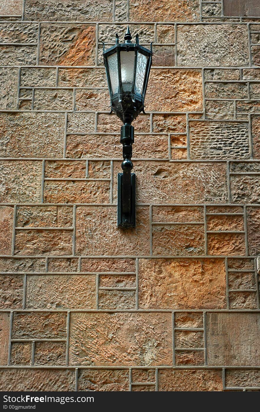 Detailed ornate black iron light fixture mounted on stone wall