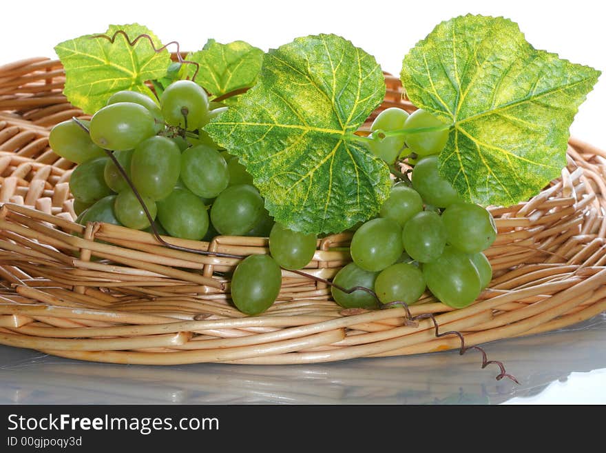 Green grape cluster with leaves on a basket