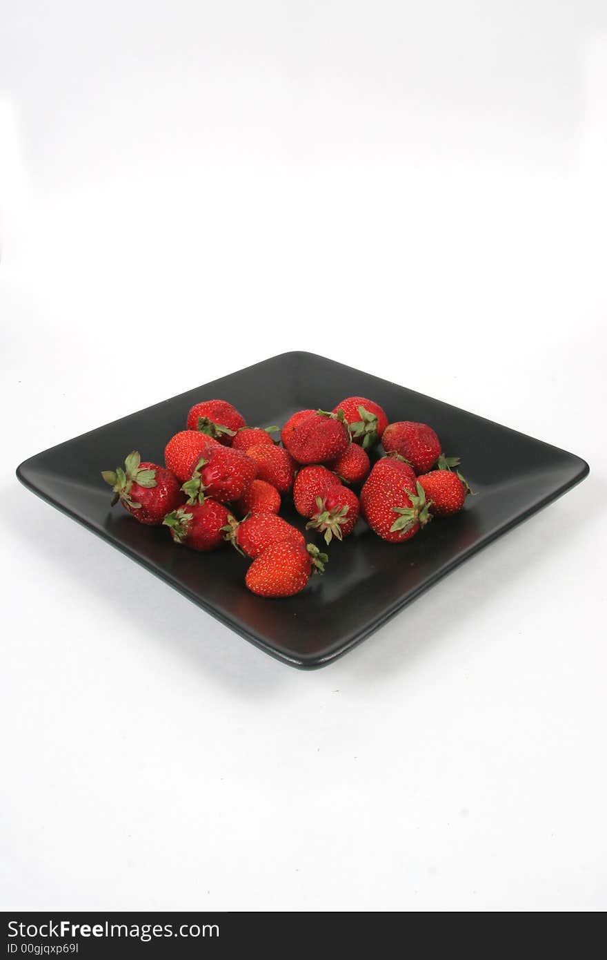 Strawberries on Black Plate over White with knife