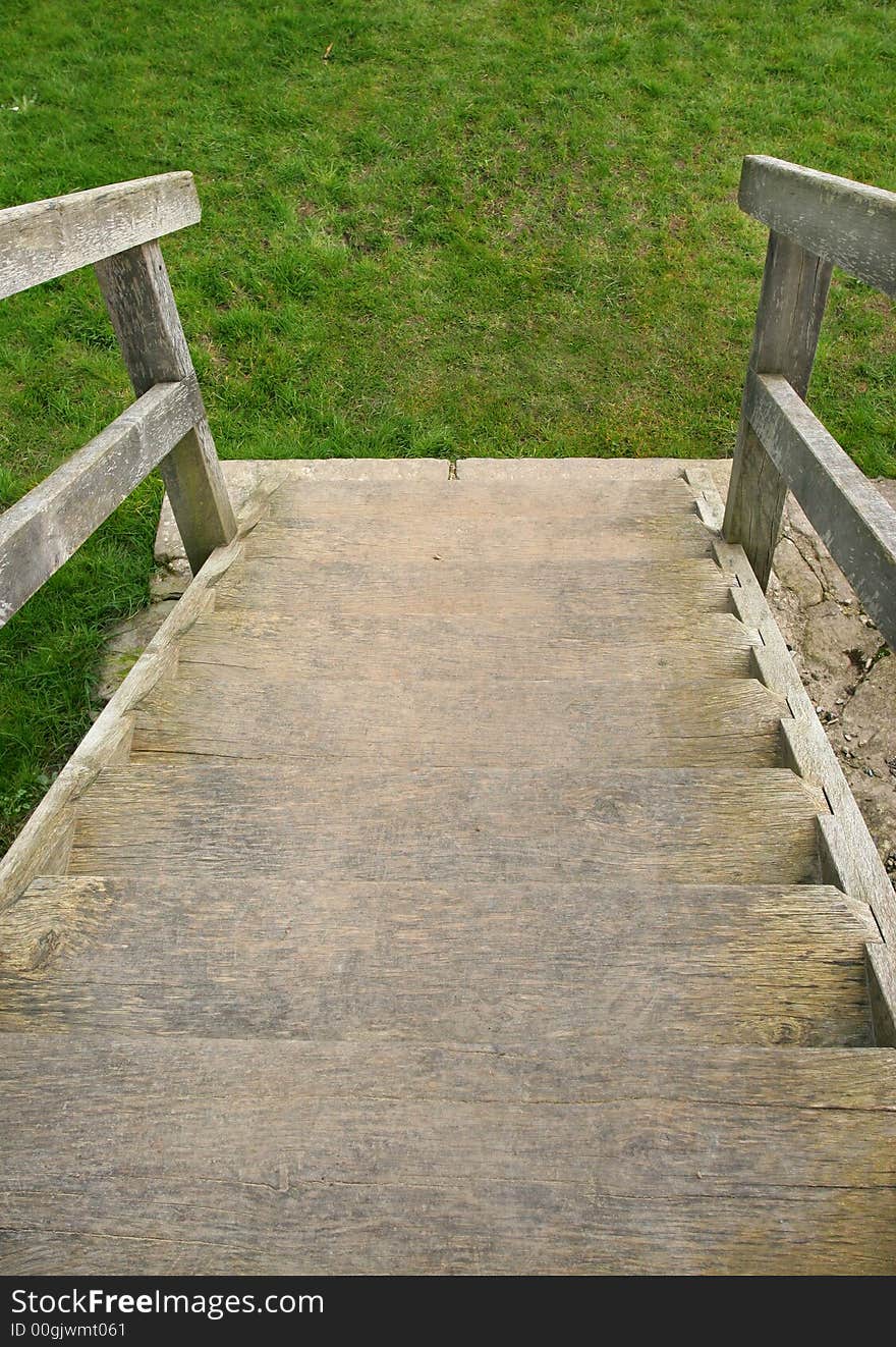Old well worn wooden outdoor staircase with the emphasis on going downwards towards grass. Old well worn wooden outdoor staircase with the emphasis on going downwards towards grass.