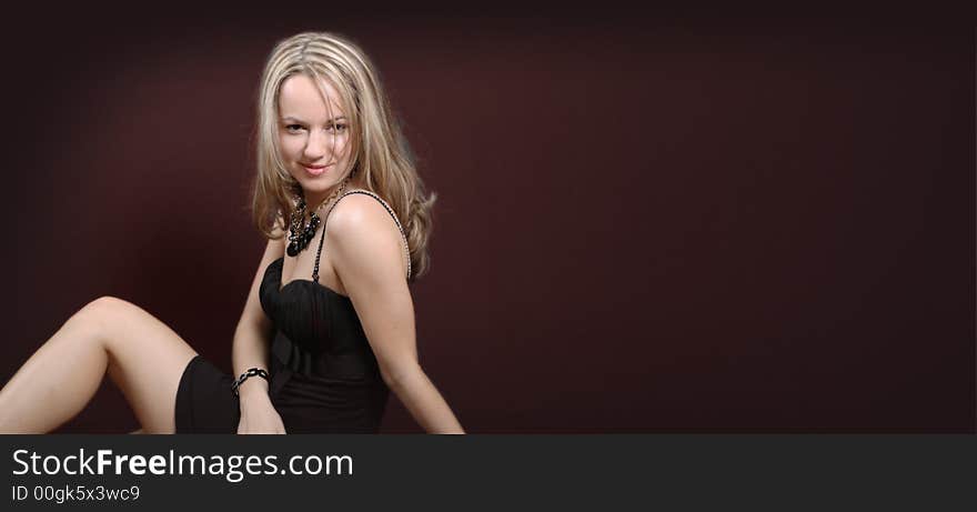 Beautiful young girl sitting near dark brown wall. Beautiful young girl sitting near dark brown wall