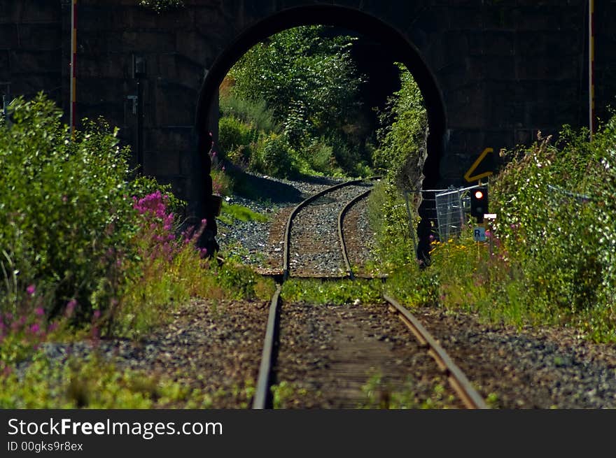 Train tracks going under a stone bridge