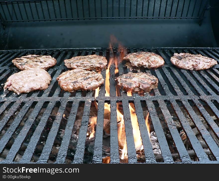 Photo of a burgers being cooked on a smoker grill. Photo of a burgers being cooked on a smoker grill