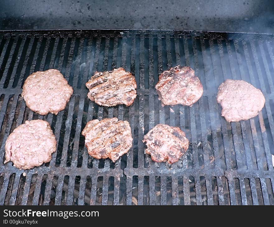 Photo of a burgers being cooked on a smoker grill. Photo of a burgers being cooked on a smoker grill