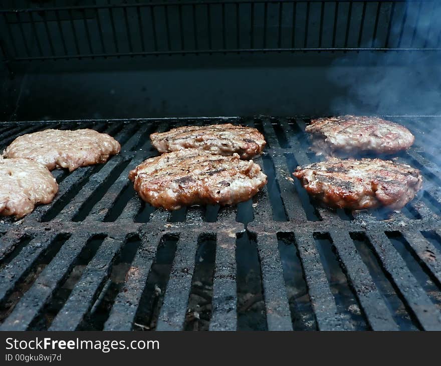 Photo of a burgers being cooked on a smoker grill. Photo of a burgers being cooked on a smoker grill