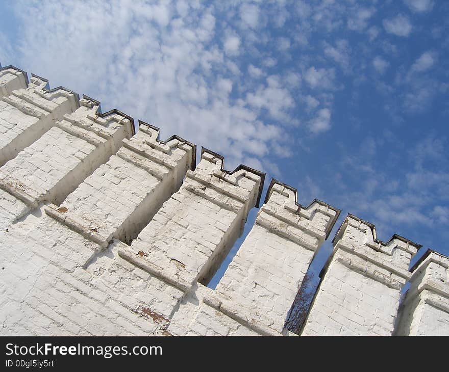 White town-wall against blue sky with rare clouds. White town-wall against blue sky with rare clouds