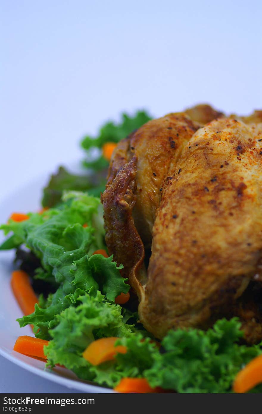 Savory whole roast chicken on a serving plate and a bed of fresh gourmet lettuce and lightly steamed carrots. White space left on top for copy. Savory whole roast chicken on a serving plate and a bed of fresh gourmet lettuce and lightly steamed carrots. White space left on top for copy.