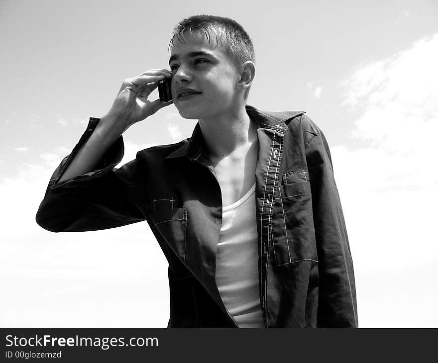 The boy calls by phone on a background of the sky. The boy calls by phone on a background of the sky