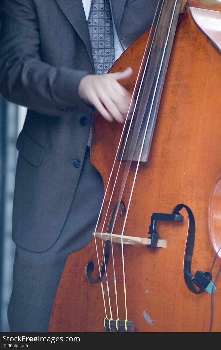 A musician in a suit and tie plays a stand-up bass.