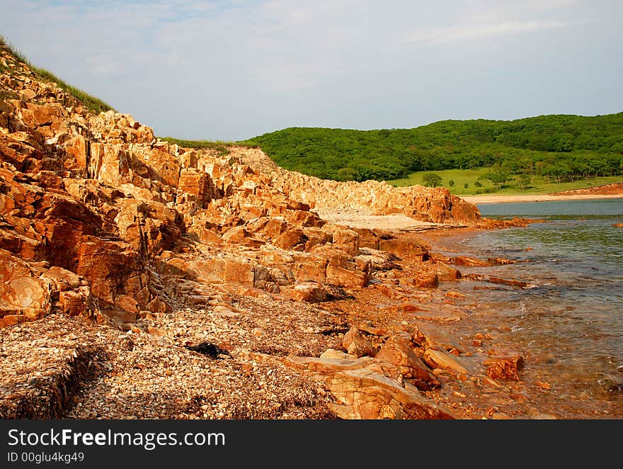 Red rocks, coast of the Pacific ocean, sea, stone beach, landscape, view, summer. Red rocks, coast of the Pacific ocean, sea, stone beach, landscape, view, summer