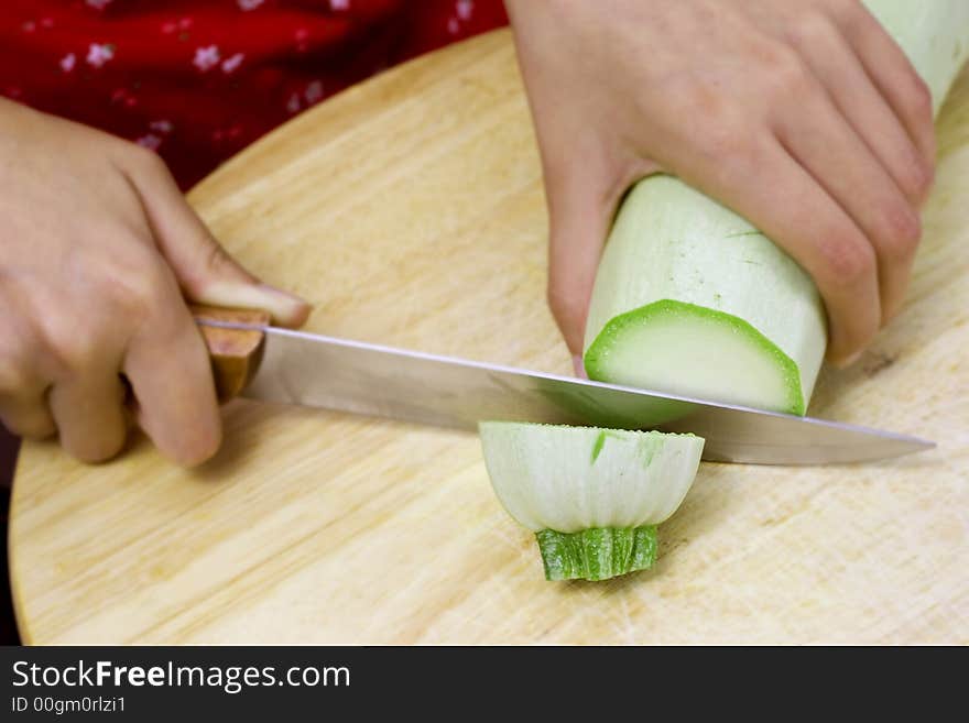 Girl cutting vegetable marrow on wood