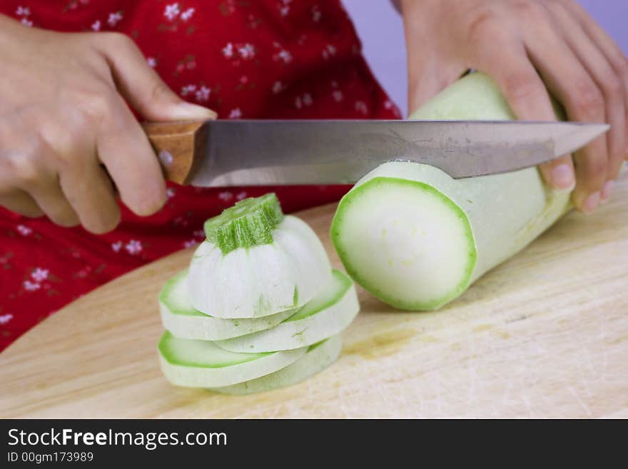 Girl cutting vegetable marrow on wood