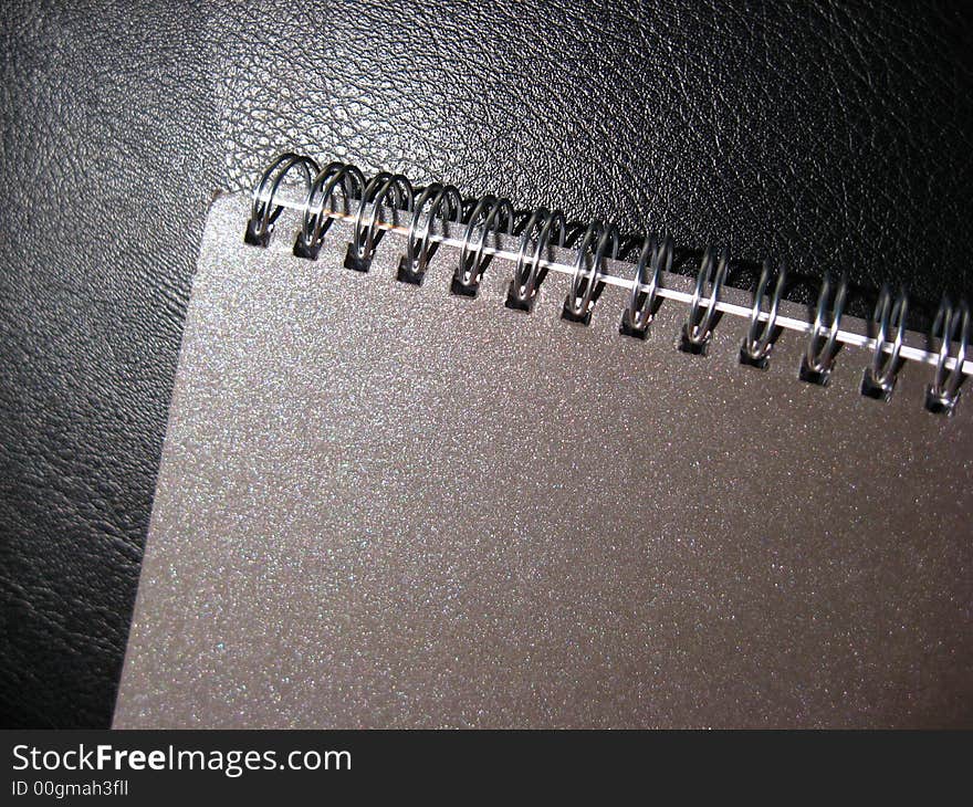 Brown Spiral Notebook on Black Leather Background. Brown Spiral Notebook on Black Leather Background