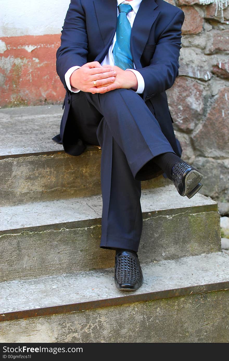 The man in a dark blue suit sits on a ladder. The man in a dark blue suit sits on a ladder