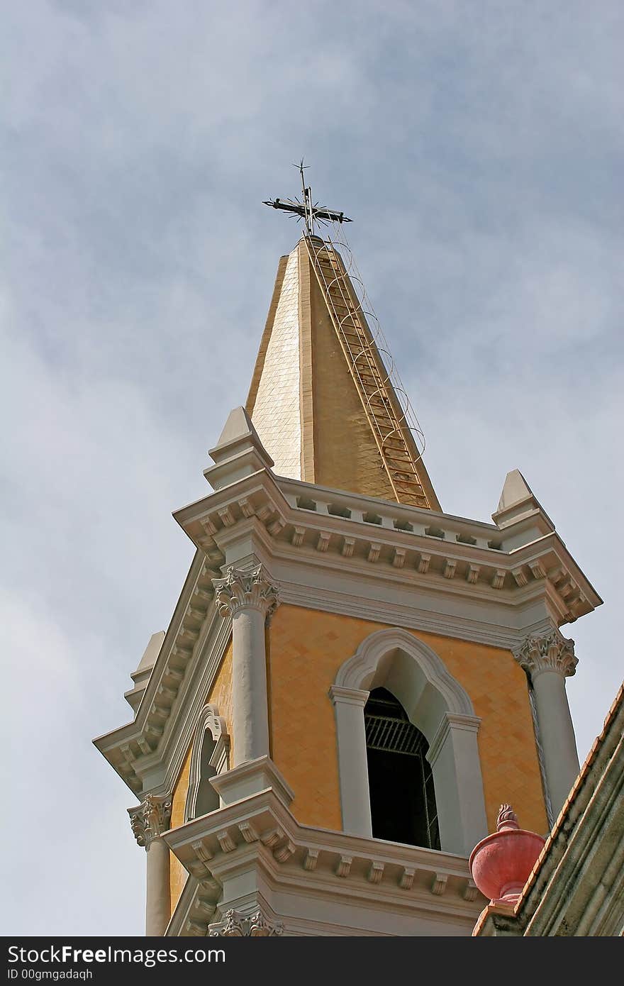 Gold steeple of Catholic church against cloudy sky. Gold steeple of Catholic church against cloudy sky