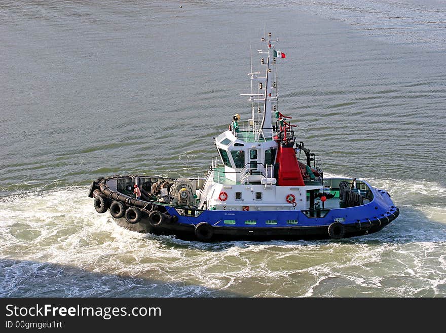 A tugboat moving through the water at a port. A tugboat moving through the water at a port