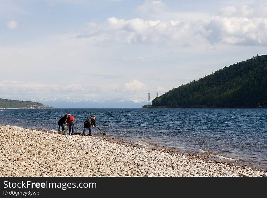 Picture of peoples scooping water from river angara with sayan's massif on back plane