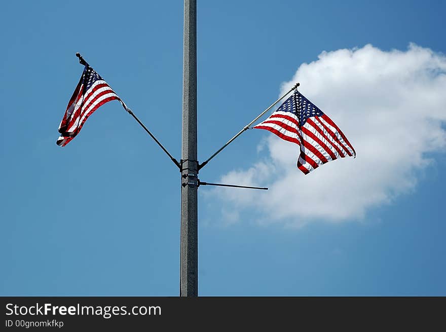 American flags on a street light pole against blue sky. American flags on a street light pole against blue sky.