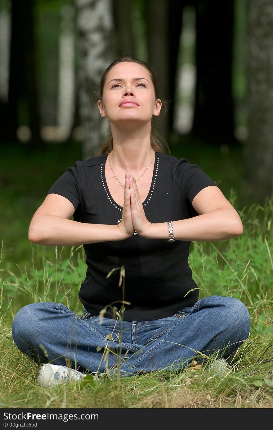 Woman doing yoga exercise on a fresh grass in a park. Woman doing yoga exercise on a fresh grass in a park