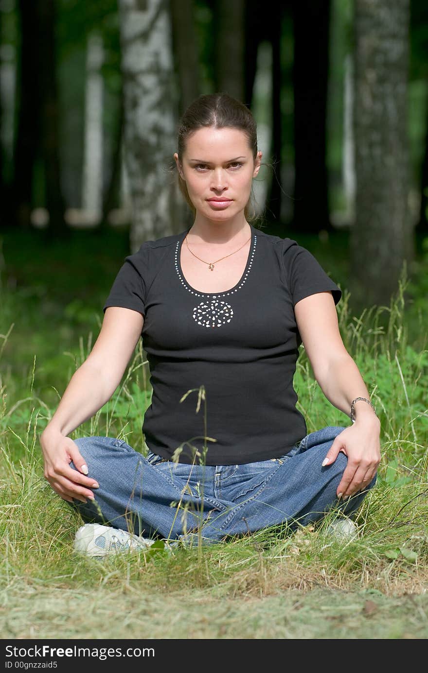 Woman doing yoga exercise on a fresh grass in a park. Woman doing yoga exercise on a fresh grass in a park