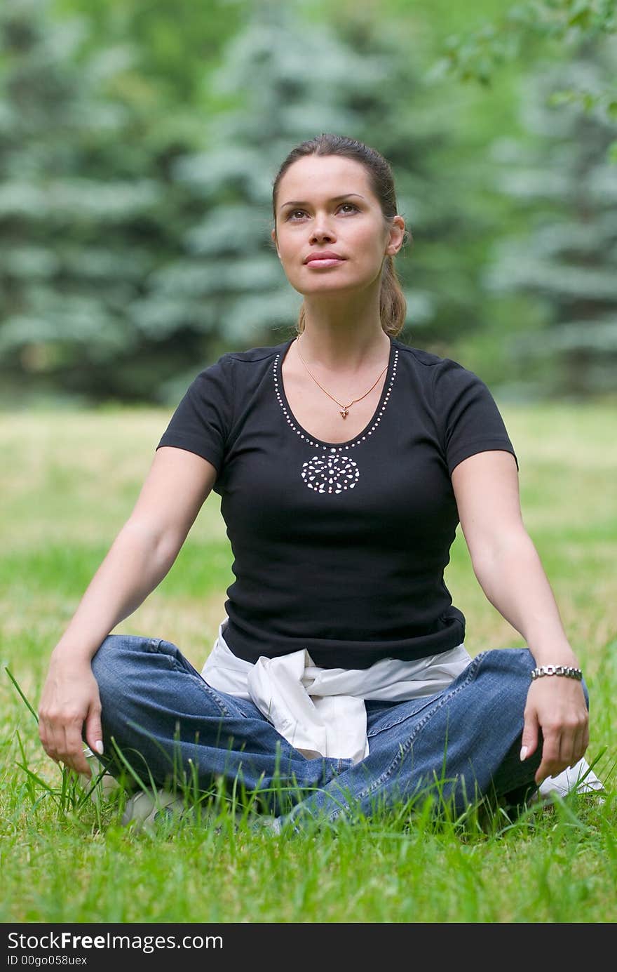 Woman doing yoga exercise on a fresh grass in a park. Woman doing yoga exercise on a fresh grass in a park