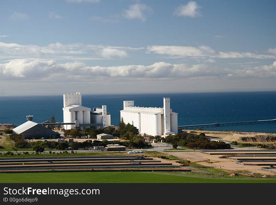 White silo with blue sea, sky and clouds in the background. White silo with blue sea, sky and clouds in the background