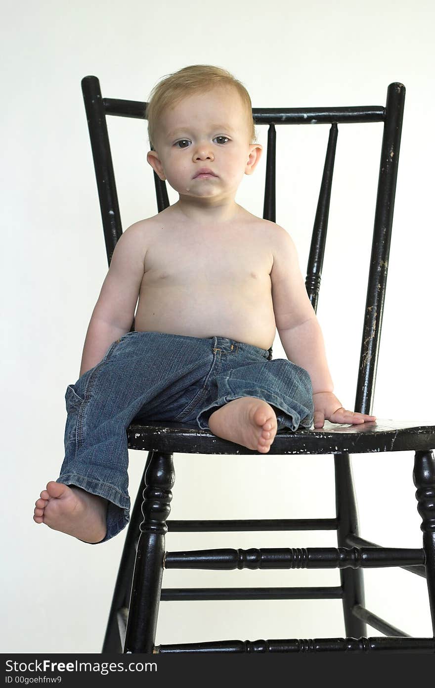 Image of a cute toddler sitting on a black chair. Image of a cute toddler sitting on a black chair