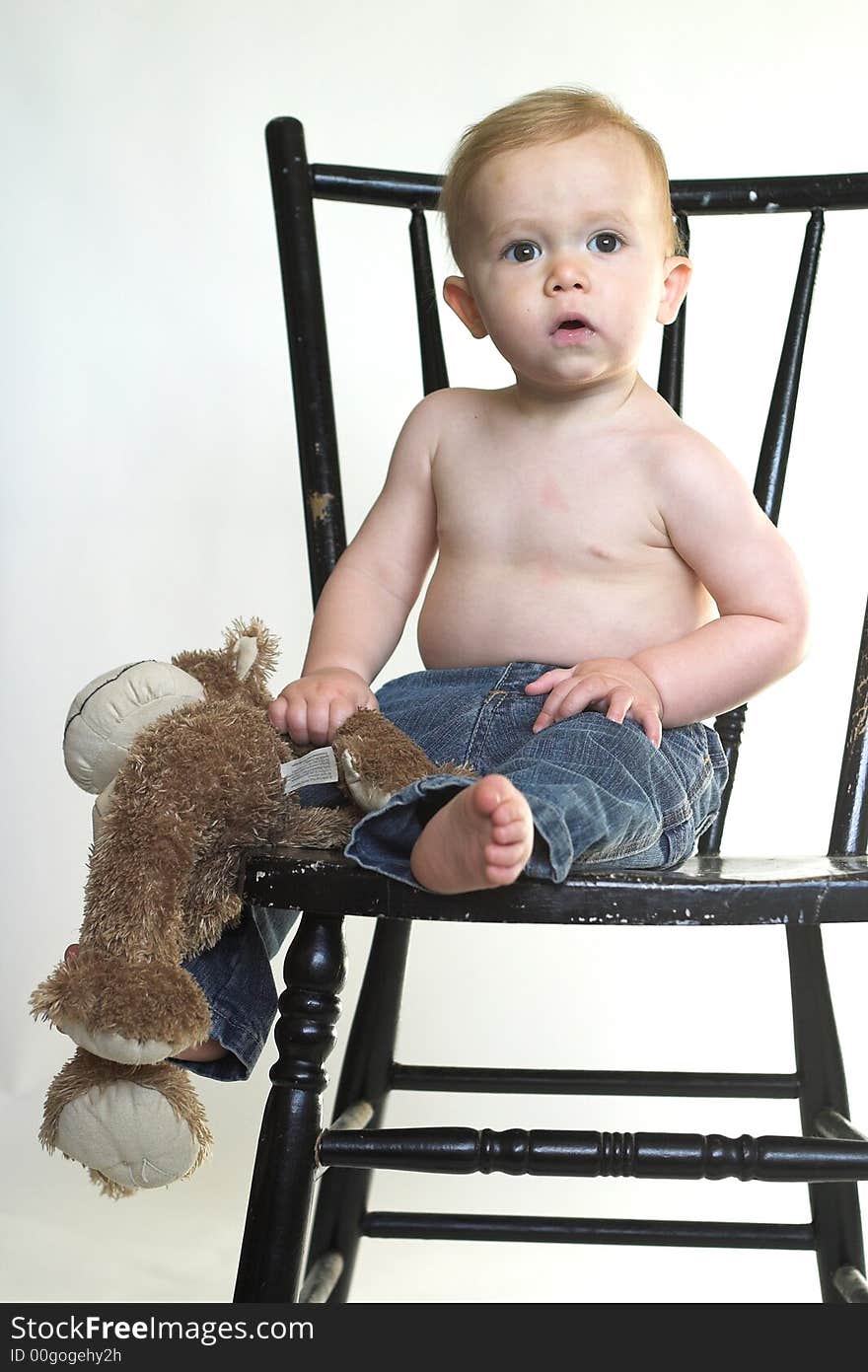 Image of a cute toddler sitting on a black chair, holding a stuffed monkey. Image of a cute toddler sitting on a black chair, holding a stuffed monkey