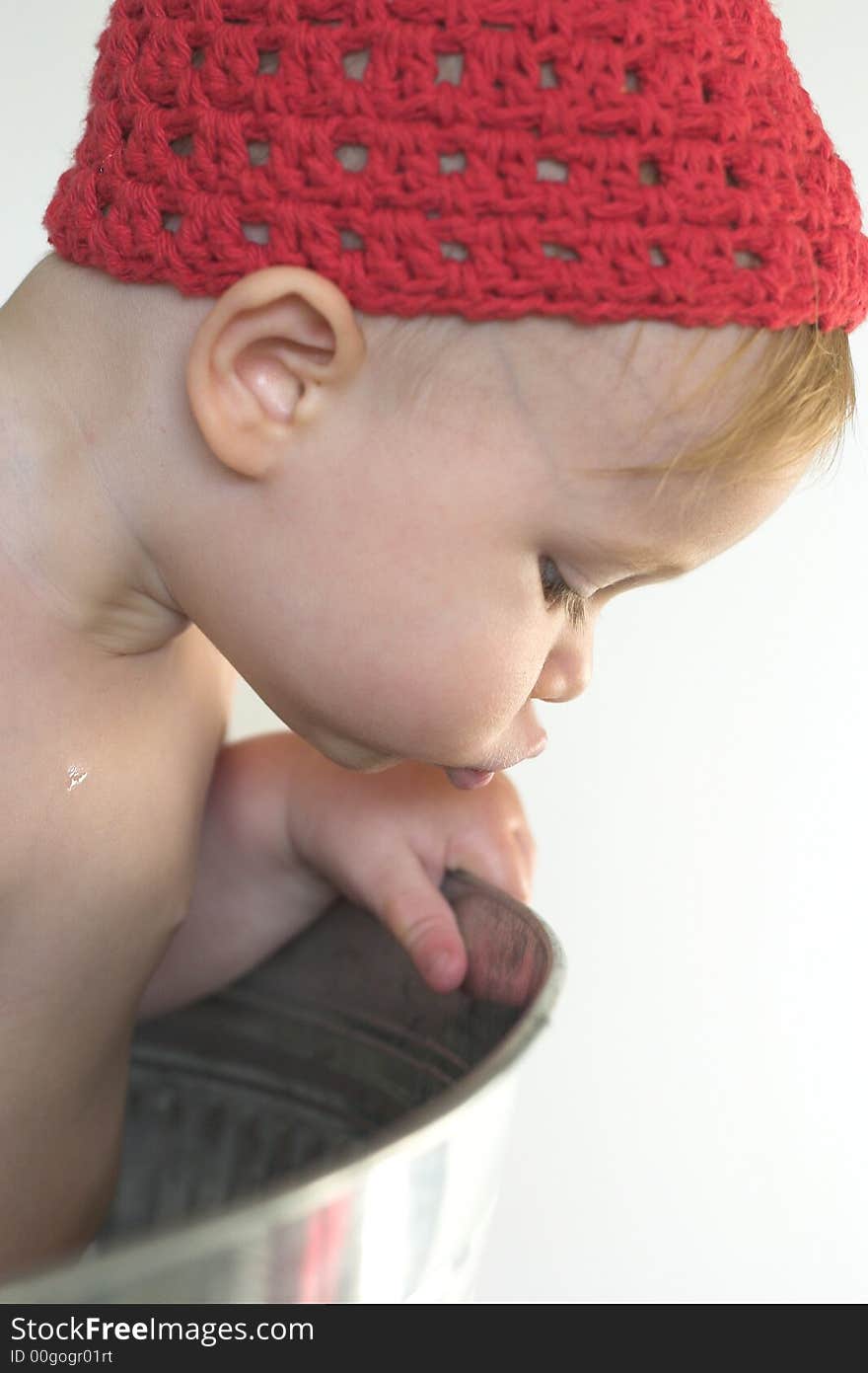 Image of cute toddler wearing a crochet cap, looking over the side of a galvanized tub