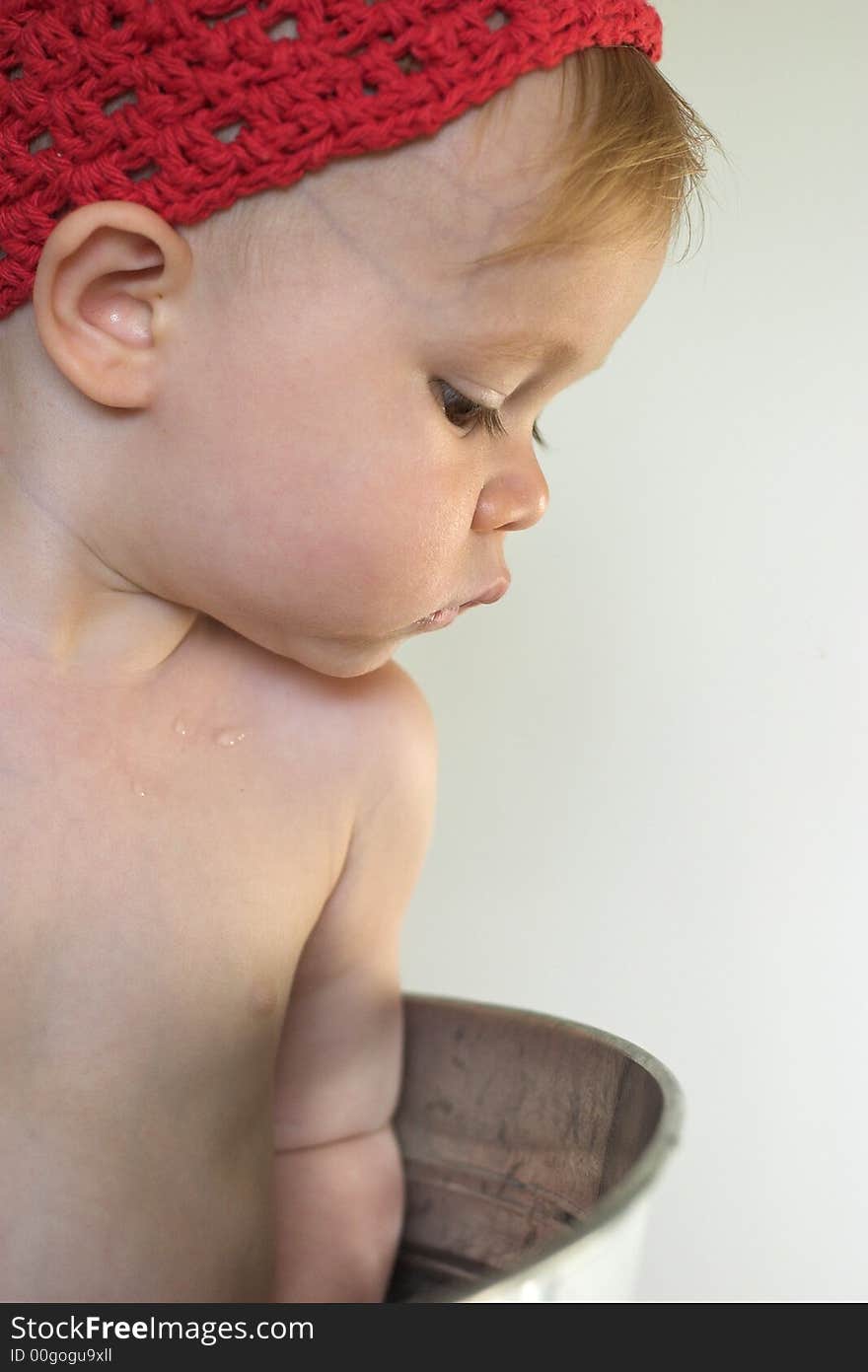 Image of cute toddler wearing a crochet cap, looking over the side of a galvanized tub