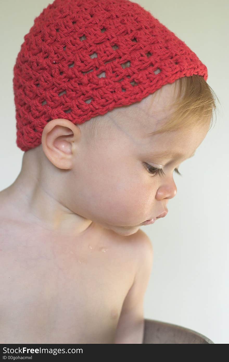 Image of cute toddler wearing a crochet cap, looking over the side of a galvanized tub