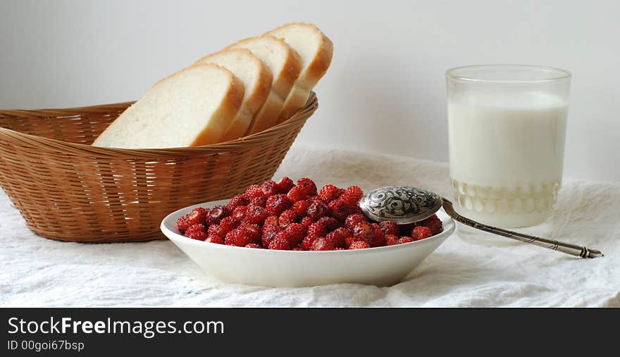 Wild strawberry, a glass of milk, and a basket of bread. Wild strawberry, a glass of milk, and a basket of bread