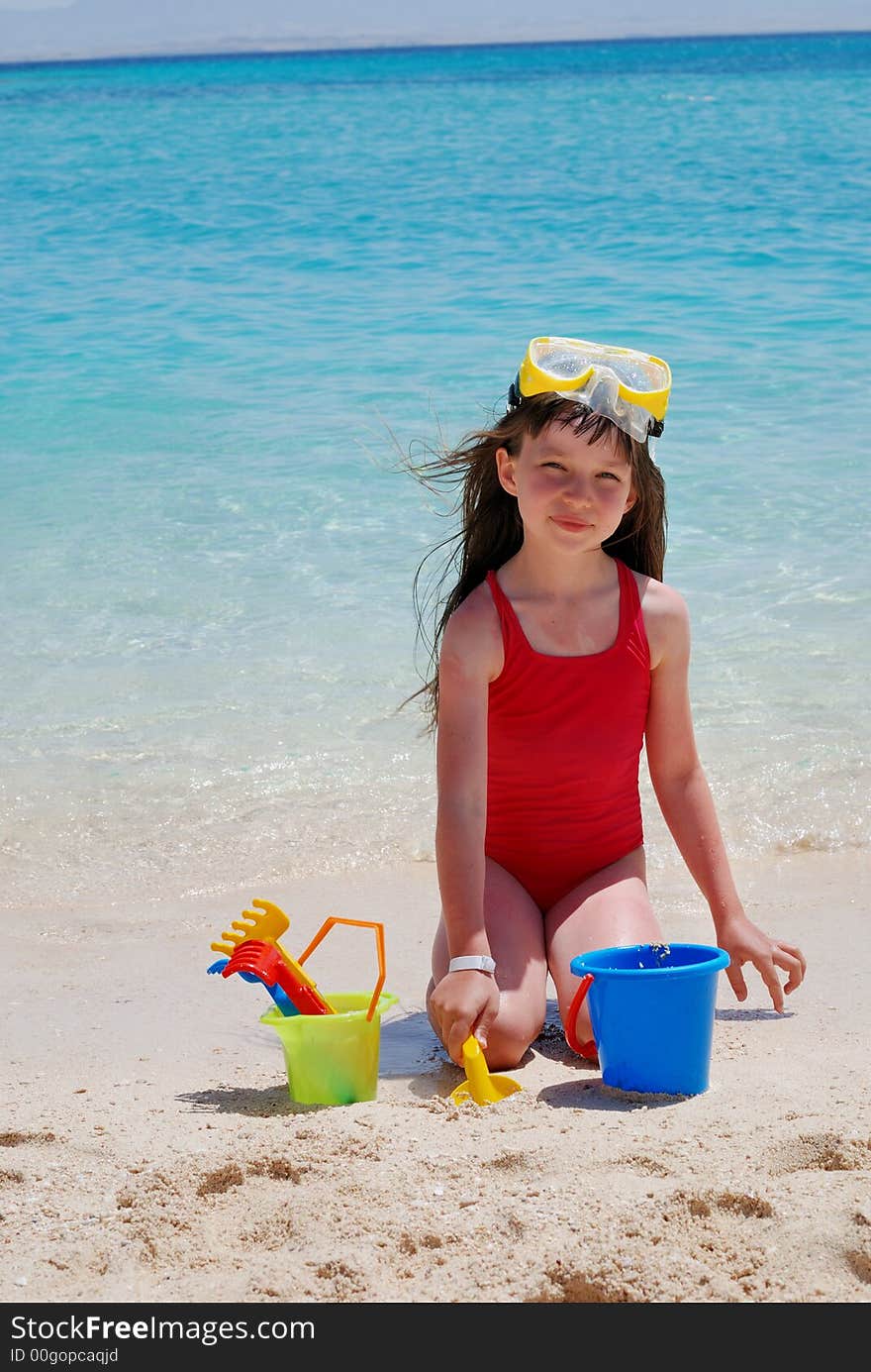 Young girl playing in the sand on the beach at a tropical island. Young girl playing in the sand on the beach at a tropical island.