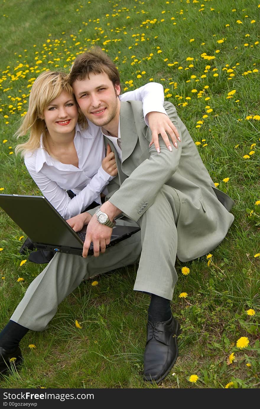 Young cheerful couple working on laptop at outdoor environment. Young cheerful couple working on laptop at outdoor environment