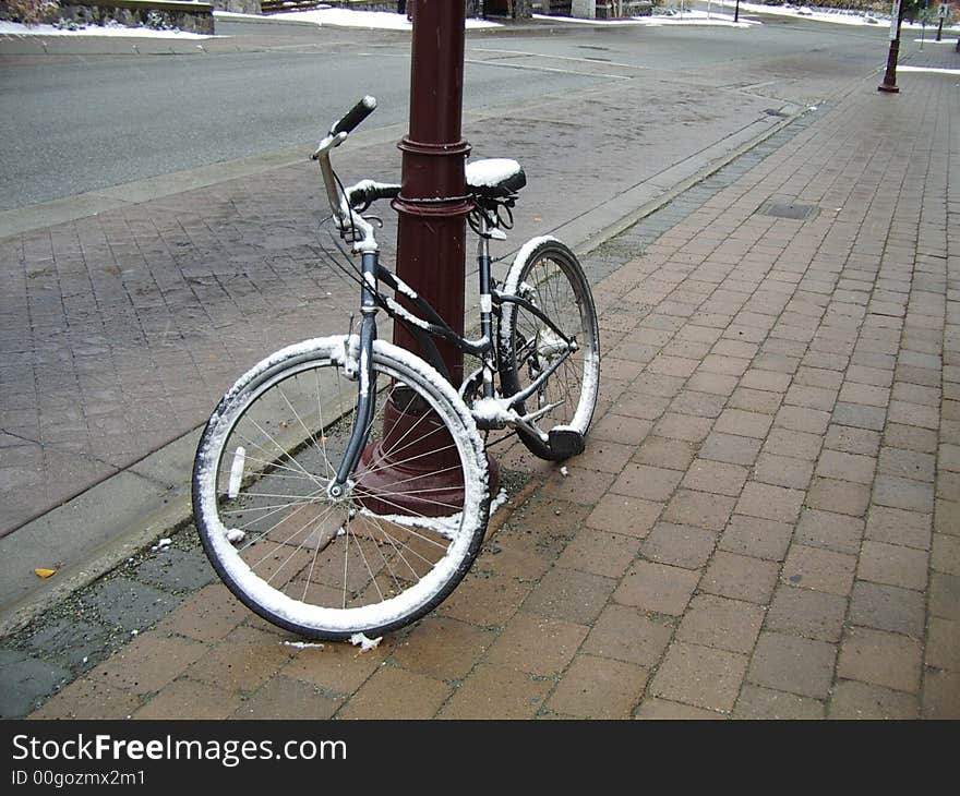 Snow covered bike leaning against a pole in Whistler Village - Creekside. Snow covered bike leaning against a pole in Whistler Village - Creekside