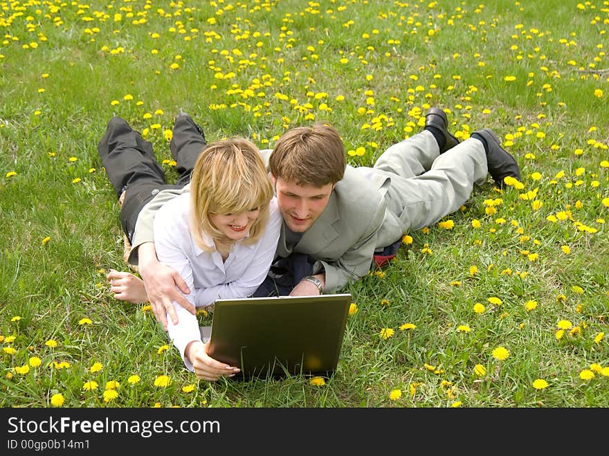 Young cheerful couple working on laptop at outdoor environment. Young cheerful couple working on laptop at outdoor environment