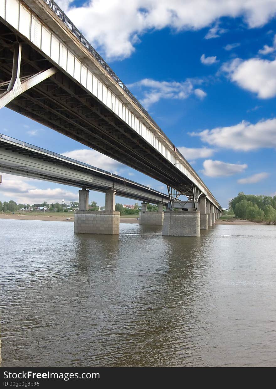 The large bridge through the river. The photo is created in the Russian province in the summer. The large bridge through the river. The photo is created in the Russian province in the summer.